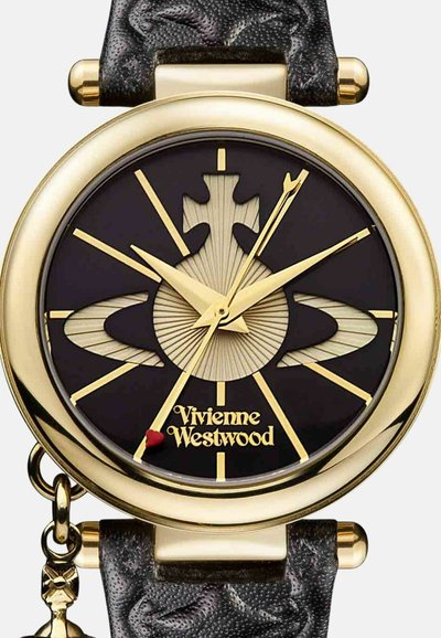 Goudkleurig polshorloge met zwarte wijzerplaat, gestileerd ornamentontwerp en goudkleurige wijzers. Gestructureerde zwarte band met bedel detail.