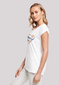 White short-sleeve t-shirt featuring a colorful diamond-shaped graphic on the chest, made from soft cotton fabric with rolled cuffs.