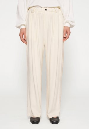 Pantaloni color crema con vestibilità rilassata, caratterizzati da una vita arricciata e un bottone singolo. Tessuto liscio con una leggera lucentezza.