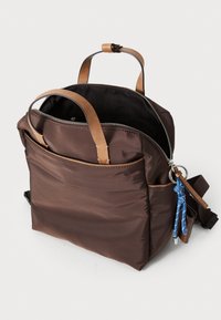 Zaino in nylon marrone con dettagli in pelle, manici superiori, chiusura con zip e tasca frontale. Include un portachiavi decorativo con dettagli blu.