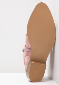 Botte de cheville en daim rose avec un bout arrondi et un zip, dotée d'une semelle en caoutchouc texturée et d'un petit talon empilé. Taille 37.