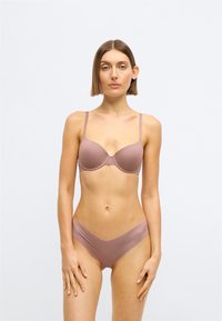 Bh en slip set in een zachte, gedempte mauve kleur. De bh heeft beugels en verstelbare bandjes; de slips hebben een low-rise, naadloos ontwerp.