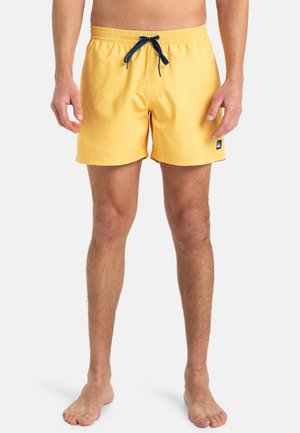 Gelbe Badeshorts mit elastischem Bund, marineblauem Kordelzug, seitlichen Taschen und einem kleinen Logo-Patch am linken Bein.