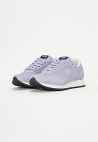Lyse lilla sneakers med en semsket finish, hvitt interiør, svart gummisåle og merking på tungen. Rund tå og snøring.