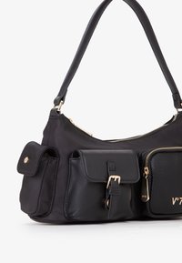 Borsa nera con corpo in nylon effetto testurizzato, dettagli in pelle, multiple tasche, accessori dorati e manico liscio. Include scomparti con cerniera.
