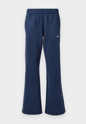 Pantalones deportivos azul marino con parte inferior acampanada, cinturilla elástica, bolsillos laterales y logo de Nike blanco en el muslo izquierdo. Textura de tela suave.