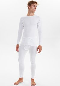 Hvid termisk langærmet top parret med hvide lange underbukser. Stoffet ser blødt og strækbart ud, med tætsiddende manchetter og et enkelt design.