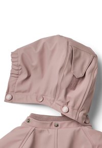 Ružová kapucňa na dažďový plášť s gombíkmi na zapnutie a elastickým sťahovaním. Má pletený golier a zapínanie na suchý zips na boku. Hladká textúra.