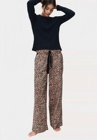 Black long-sleeve top, soft fabric, paired with loose leopard-print pajama pants featuring a drawstring waist in a light tan and black pattern.