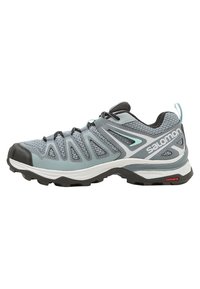 Chaussure de randonnée gris clair avec tige en mesh, capot en caoutchouc à l'avant, semelle intermédiaire blanche et semelle extérieure noire. Présente un logo de marque proéminent et des accents de design.