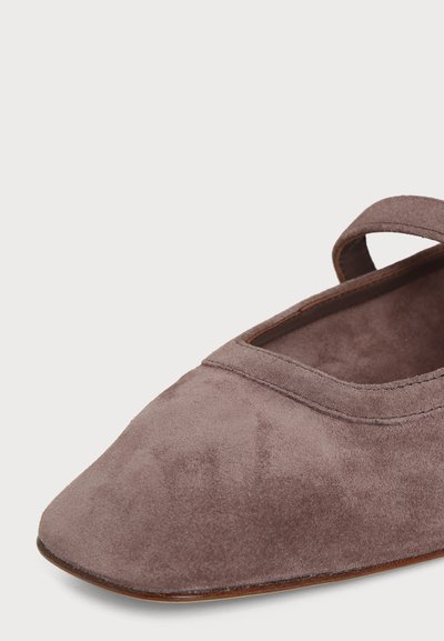 Chaussure plate en daim marron doux avec un bout carré et une bride unique sur le dessus.