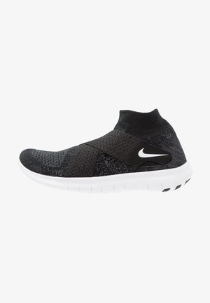 Zapatilla deportiva negra con parte superior de tejido, paneles de malla, una correa ancha y suela blanca con agarre texturizado. Logo de Nike en el lateral.