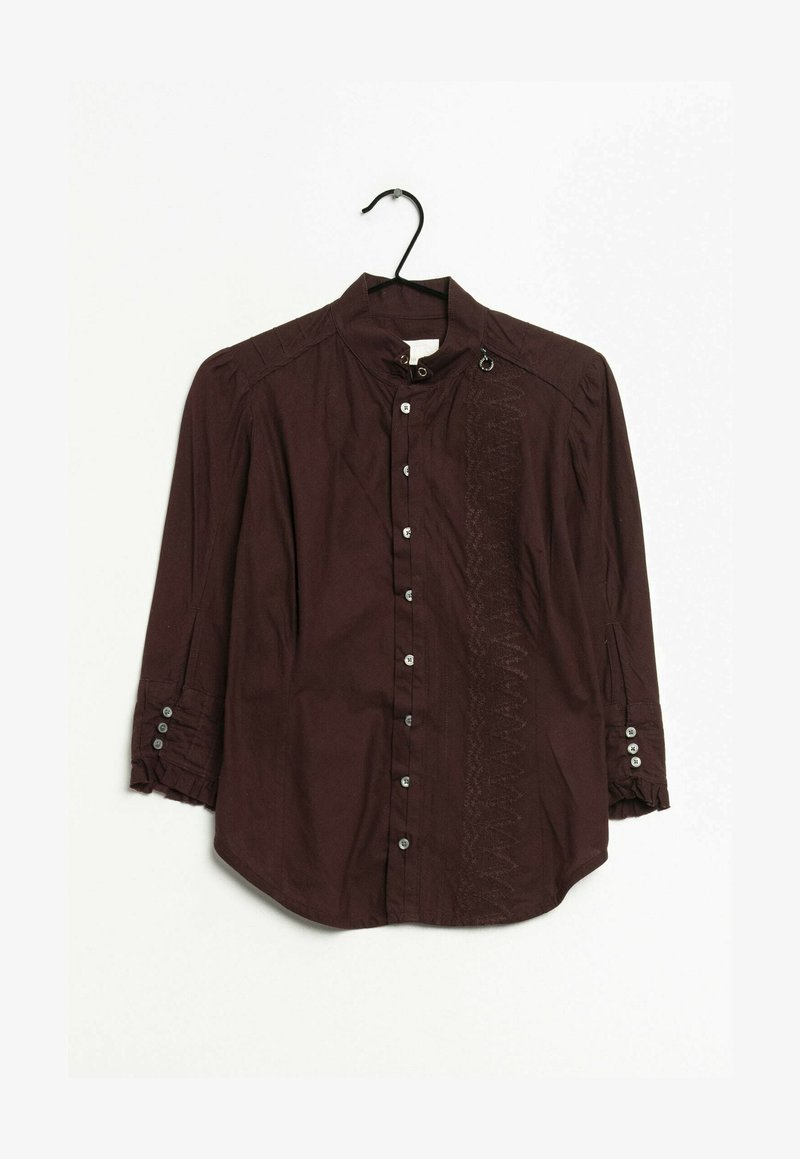 Blouse marron foncé à manches longues avec boutons sur le devant, col montant, détails cousus d'un côté et poignets boutonnés sur un cintre noir.