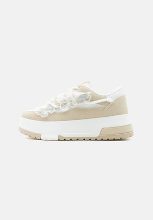 Beżowo-białe sneakersy na platformie z siateczkowymi panelami, kwiecistym haftem na sznurowadłach oraz grubą teksturowaną podeszwą.