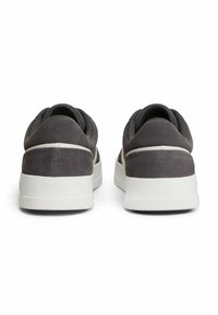 Sneakers in suede grigio con accenti in tessuto nero, dotati di una suola in gomma bianca e marchio impresso sul tallone. Design classico a profilo basso.