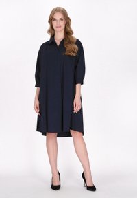 Marineblaue Hemdkleid mit kragenlosem Ausschnitt und Dreiviertelärmeln. Hat eine lockere Passform und einen asymmetrischen Saum. Glatte Stofftextur.