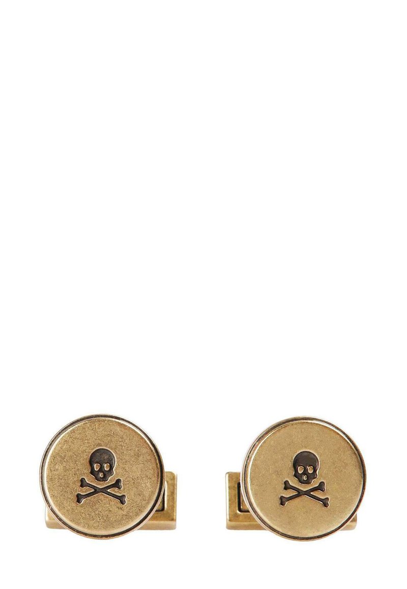 Gemelos de tono dorado con forma circular que presentan un diseño de calavera y huesos cruzados en color negro grabado en la superficie frontal.