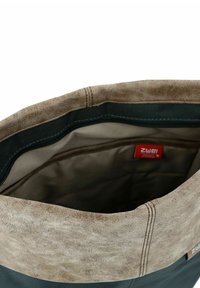 Bruine neplederen tas met een brede opening, voorzien van een gladde binnenvoering en een klein rood label binnenin. Gelaagd exterieur met stikdetails.