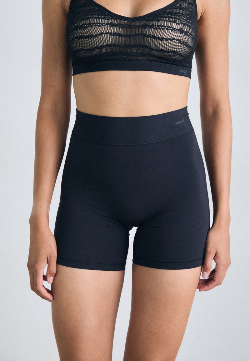 Bermudas noires taille haute en tissu extensible, dotées d'une texture lisse et de coutures minimales pour le confort et un bon ajustement.