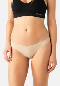 Culotte hipster en coton beige avec une texture douce et une ceinture élastique. Une branding subtile est visible sur la ceinture.