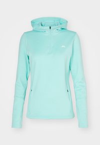 Světle modrý mikina s kapucí vyrobená z materiálu odvádějícího vlhkost, má přední zip do půlky a boční kapsy. Logo na hrudi.