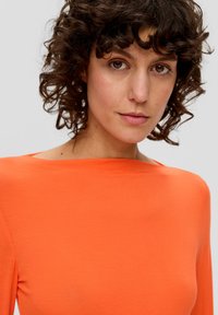 Oranges, langärmliges Oberteil mit weitem Ausschnitt, aus einem weichen, glatten Stoff gefertigt. Einfaches Design mit körpernahem Schnitt, ohne sichtbare Muster oder Akzente.