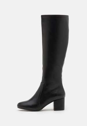 Botte en cuir noire montant jusqu'au genou avec bout arrondi et talon bloc, vue de côté sur fond blanc.