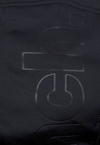 Czarny materiał sportowy z subtelnym, wytłoczonym nadrukiem logo. Gładka faktura ze lekkim rozciągnięciem, bez dodatkowych wzorów ani akcentów.