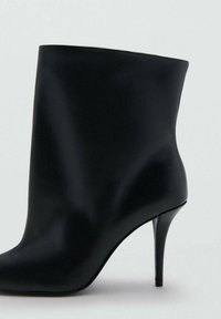 Črni gležnar iz gladkega usnja z zaključkom v koničasto obliko in tanko visoko peto. Enostavna zasnova, brez vidnih kovinskih detajlov ali okraskov.