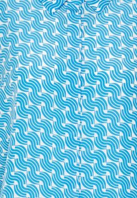 Camicia a maniche corte con un motivo ondulato in tonalità blu su sfondo bianco, con colletto e dettagli di bottoni discreti.