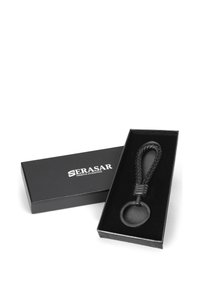Black braided leather keychain in a black presentation box with a smooth circular ring and metallic accents. Box features brand logo.