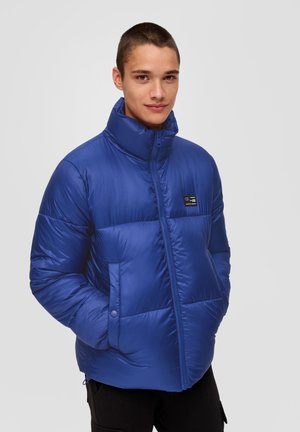Doudoune bleue avec un col montant, design matelassé, fermeture éclair avant et poches latérales. Fabriquée en matériau léger et brillant.