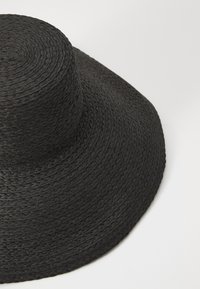 Zwarte strohoed met een brede, platte rand en een afgeronde top, voorzien van een geweven textuur en een constante zwarte kleur.