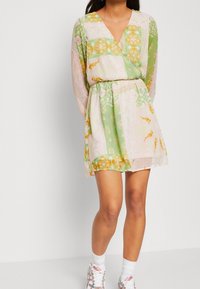 Sukienka kopertowa w pastelowej zieleni i różu z kwiatowymi wzorami, długimi rękawami, głębokim dekoltem w serek i elastyczną talią. Lekka, cienka tkanina.