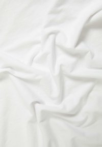 Weißer Stoff mit einer weichen, glatten Textur, die Falten und Falten zeigt und die leichte und gut fallende Beschaffenheit hervorhebt.