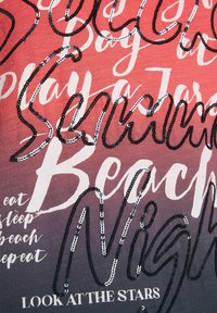 Camiseta con un diseño degradado que pasa de coral a gris, con texto en lentejuelas en negro y plata con frases sobre la playa y las noches.