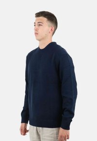 Maglione lavorato a maglia blu navy con scollo rotondo, polsini e orlo a coste, caratterizzato da una vestibilità classica e una texture liscia.