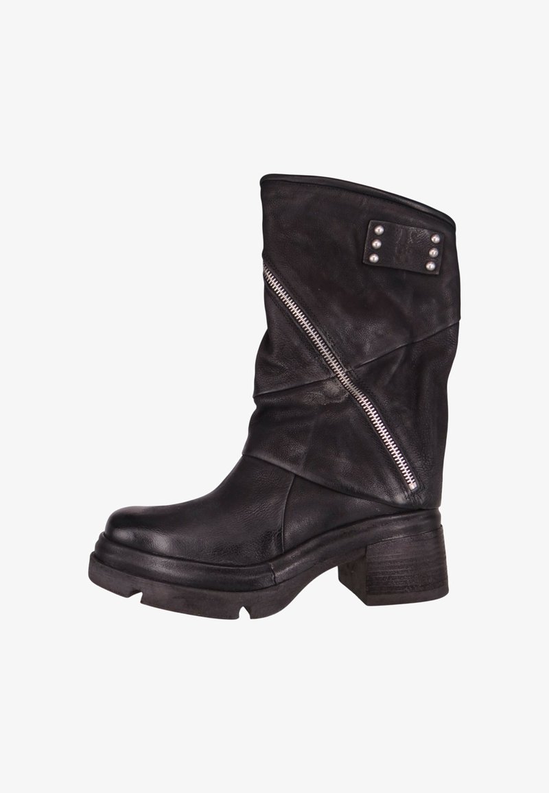 Bota corta de cuero negro con diseño holgado, detalle de cremallera plateada y adorno de tachuelas en el caña. Suela gruesa y tacón cuadrado.