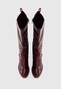 Vīnogu krāsas ādas zābaki līdz ceļiem ar teksturētu augšdaļu un gludu apakšējo daļu; aprīkoti ar apaļu purngalu un aizmugures cilpu ērtai uzvilkšanai.