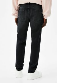 Musta suorat farkut, joissa on kaksi takataskua ja sileä pinta. Yhdistetty valkoisiin tennareihin.