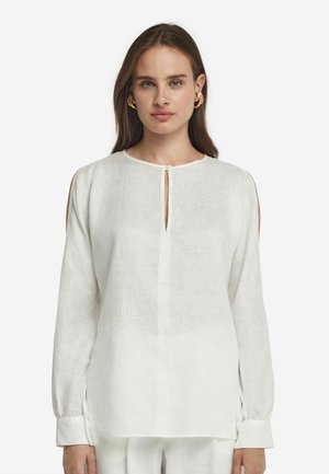 Hvid linnedbluse med lange ærmer, rund halsudskæring, nøglehul detalje foran og sidelufter. Blødt, tekstureret stof.