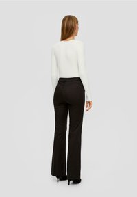 Zwarte flare-pantalon, nauwsluitend om de taille met een gladde textuur. Gecombineerd met een witte ribbeltrui met lange mouwen. Eenvoudig en stijlvol ontwerp.