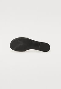 Semelle de chaussure à talon haut noire, présentant une semelle en caoutchouc lisse et un accent transparent au niveau du talon. Design épuré avec un minimum de détails.