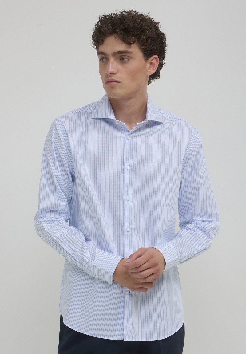 Camicetta a maniche lunghe a righe blu chiaro realizzata in un tessuto con una texture liscia. Presenta un colletto classico e una chiusura con bottoni davanti.