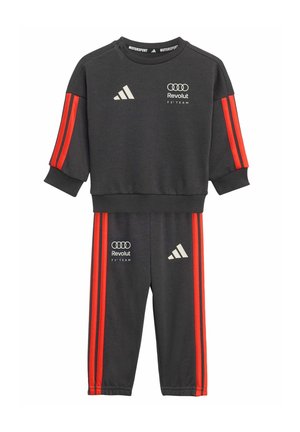 Dunkelgrauer Trainingsanzug mit roten Streifen, bestickt mit einem Logo auf Brust und Oberschenkel. Weicher Stoff, lockere Passform, gerippte Bündchen.