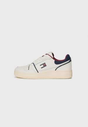 Baskets en cuir blanc avec accents bleu marine et bordeaux, détails perforés et semelle texturée. Présente un logo sur le côté extérieur.