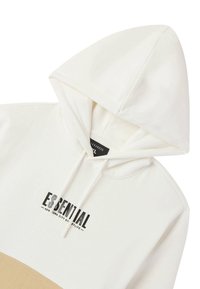 Felpa bianca con un pannello inferiore beige, con il logo "ESSENTIAL" in nero. Ha un cappuccio con lacci e un tessuto morbido e strutturato.