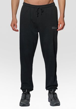 Zwarte sweatpants van zacht materiaal met een tailleband met trekkoord, voorzien van ribgebreide boorden en een subtiele logodetail aan de voorkant.