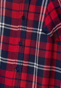 Rood en marineblauw geruit overhemd met knoopsluiting, voorzien van een pied-de-poule patroon en witte accentlijnen. Zachte stof met een gestructureerd uiterlijk.