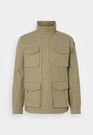 Beżowa kurtka z wysokim kołnierzem, czterema przednimi kieszeniami, kieszenią na suwak na rękawie i lekko fakturowanym materiałem.